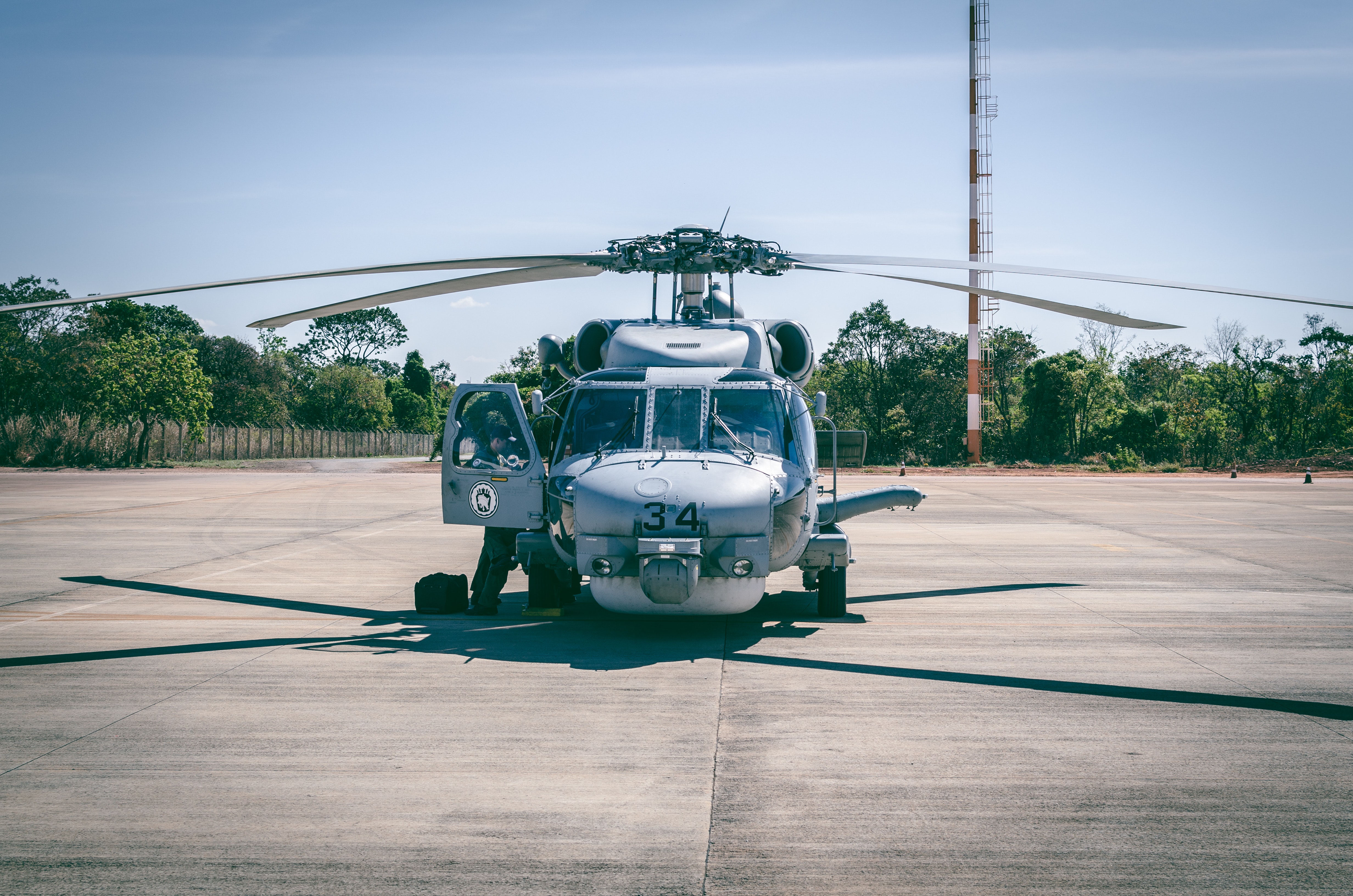 Hay un helicóptero en el centro de la imagen, pronto para despegar. Hay árboles en el borde del predio