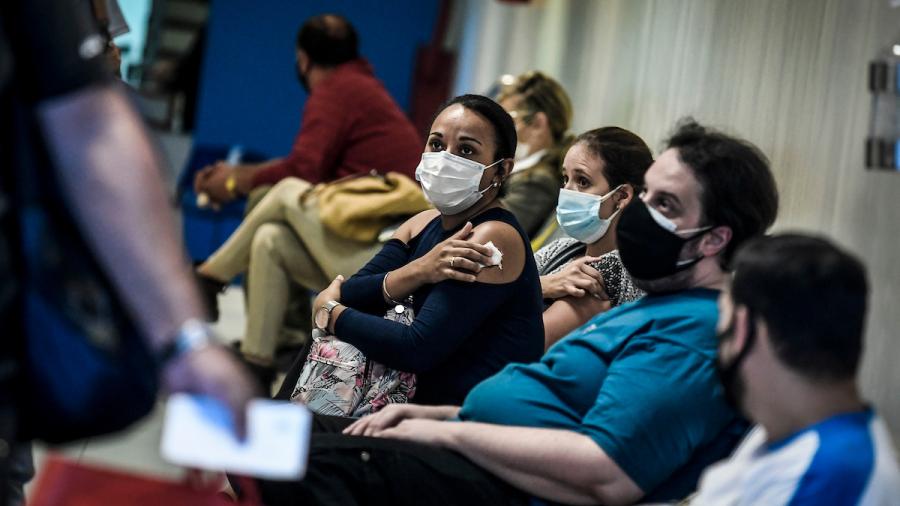 Centro de vacunación Covid 19 - Pacientes sentados en sala de espera, algunos ya vacunados y otros esperando a ser vacunados.